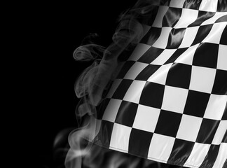 Racing flag with black and white checkers in smoke on dark background