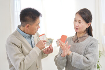 ポチ袋を持ってお年玉の金額を相談するシニア男性と女性