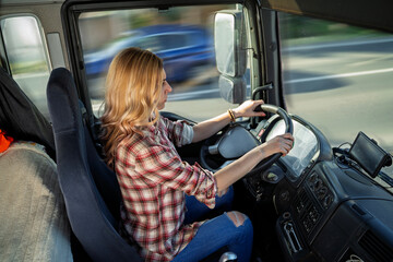 Young confident woman professional truck driver in casual clothes driving a truck, shot from inside...