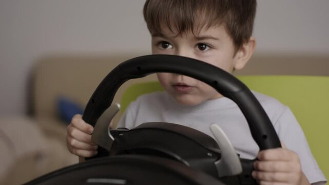Boy Playing Racing Video Game in Game Console. Child Playing Computer Game in Headphones With Steering Wheel. Gamer With Headset Holding Steering Wheel Playing Video Game. Kid Gambling Addiction.