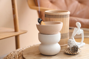 Bowl with Palo Santo, incense and statuette on board in room, closeup