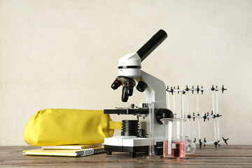 Modern microscope with chemical flasks, molecular model and pencil case on wooden table against...