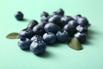 Heap of fresh ripe blueberry on turquoise background, closeup
