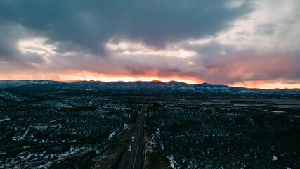 sunset over snowy mountains with highway in foreground