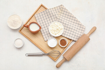 Wooden board with different ingredients for preparing sweet cinnamon roll on white background