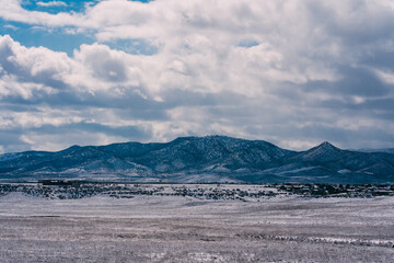 snowy desert and mountain landscape with cloudy sky
