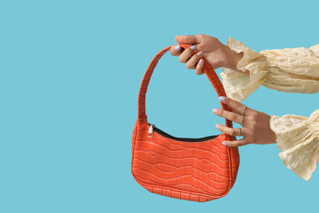 Female hands with stylish manicure and handbag on color background