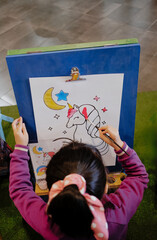 Girl drawing and painting on a canvas in a room