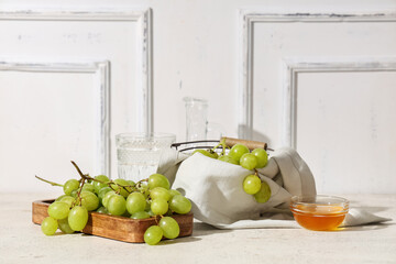 Wooden board and basket with sweet ripe grapes on white background