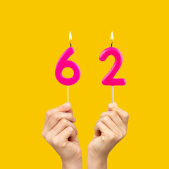 Birthday number 62 - Hands holding fuchsia colored candles