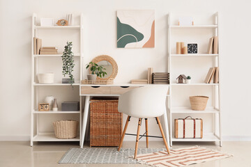 Interior of stylish modern room with workplace and shelving units near white wall