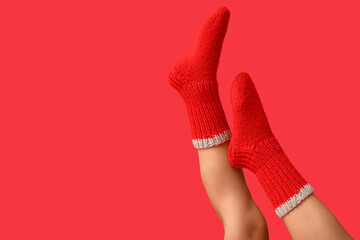 Legs of young woman in red knitted socks on color background