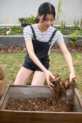 Woman adding dried leaves to a compost bin