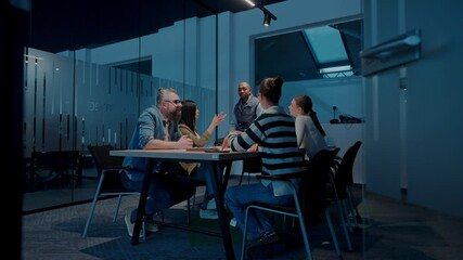 In a sleek glass office space, a team of business professionals engage in lively discussions and exchange strategic ideas, showcasing collaboration and innovation at the heart of modern corporate