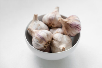 Bowl with fresh garlic on white background
