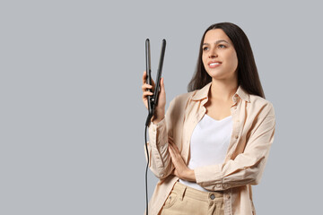 Fototapeta premium Pretty young woman with hair straightener on white background