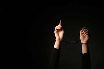 Female hands in handcuffs on black background