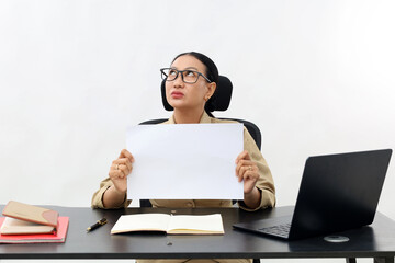 Female teacher in civil servant uniform with paper and laptop on the desk showing blank paper and...