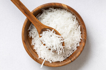 Freshly grated coconut in a wooden bowl, top view