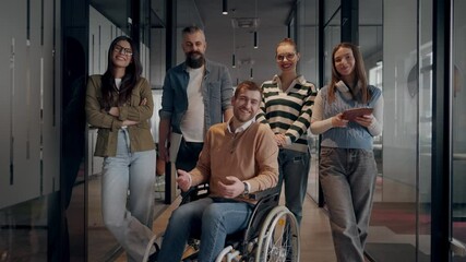 A businessman with disability in a wheelchair is surrounded by supportive colleagues in a modern office, showcasing the strength of teamwork, inclusivity, and empowerment in the face of challenges. 