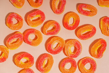 Peach rings scattered on a light surface, colorful gummy candies