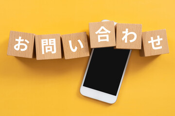 お問い合わせと書かれたブロックとスマホ