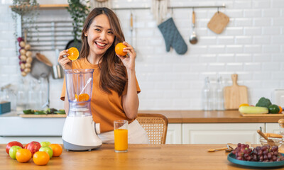 Portrait of beauty healthy asian woman making orange fruit smoothie with blender.girl preparing cooking detox cleanse with fresh orange juice in kitchen at home.health, vitamin c, diet, healthy drink