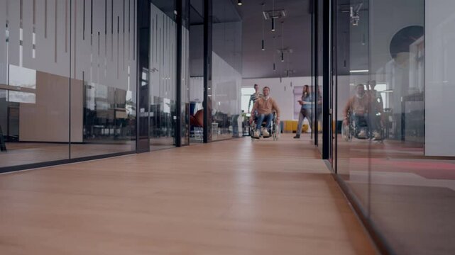 Modern startup coworking office corridor with glass walls, featuring a man with disabilities in a wheelchair. The space showcases an inclusive, accessible workplace with a sleek, open design and
