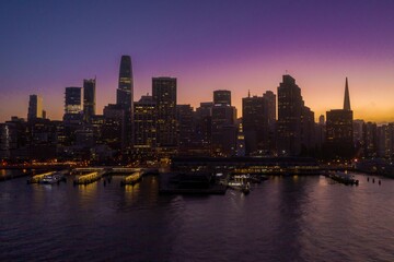 Obraz premium San Francisco's skyline is silhouetted against a vibrant sunset sky in the United States. The city's iconic buildings stand tall, creating a dramatic and captivating urban landscape.