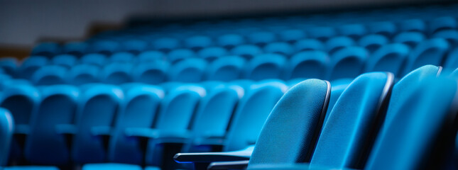 Fototapeta premium Rows of Empty Blue Theater Seats in Dimly Lit Auditorium Offering Copy Space and Geometric Repeating Pattern