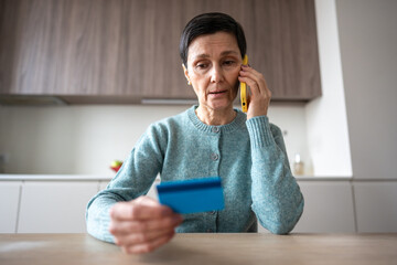Financial phone scam. Nervous stressed frightened woman sending money to fraudsters via phone....
