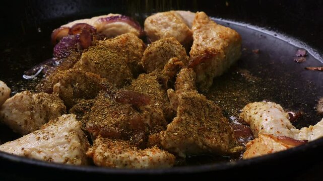 Chicken pieces fried in sauce and spices in a frying pan. Medium shot.