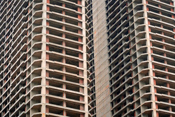 Tall concrete structures rise in an urban setting, showcasing incomplete frameworks and open...