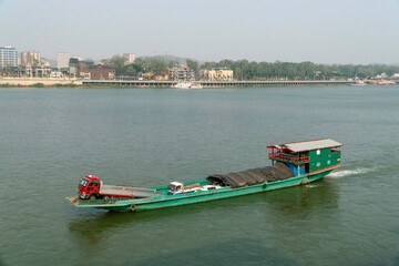 CHIANG SAENN, THAILAND - APRIL 30, 2024: A boat loaded with cars sails along the Mekong River...