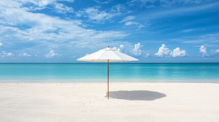Fototapeta premium an umbrella on a sandy beach with a blue sky in the background.