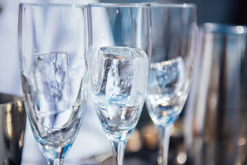 Three empty wine glasses with a large ice cube, preparations for the celebration, wine and champagne tasting, blurred background, selective focus. Preparing a coctail party event