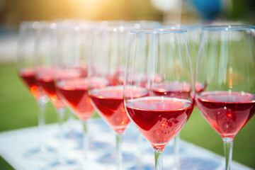 Glasses with red wine. Catering services. glasses with wine in row background at outdoor party. Shallow depth of field