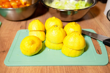 Halved lemons on cutting board for cooking. Several halved lemons are arranged on a green chopping...
