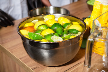 Used citrus halves soaking in stainless steel bowl. A metal bowl filled with juiced lemon and lime...