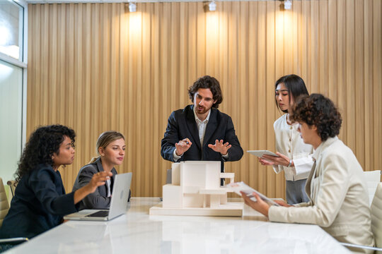 Architects engineers collaborating on building design project in modern office, diverse team of professionals female muslim architect and male engineers discussing architectural model of structure - Powered by Adobe