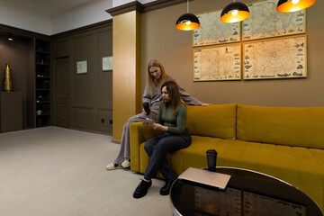 Obraz premium Friends enjoy a cozy afternoon discussing plans while seated on a vibrant yellow sofa in a stylish living room
