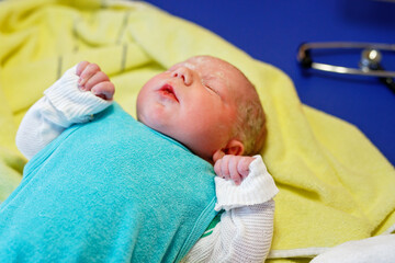 Newborn child crying seconds and minutes after birth. Cute tiny new born baby girl on towel. New life, beginning, healthcare.