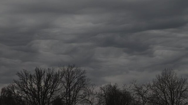 A dramatic display of undulatus asperatus clouds forms wavy, textured layers across the sky, creating a surreal and turbulent atmosphere. Includes copy space.