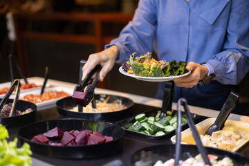 Close-up of a woman choosing vegetables at a salad bar