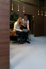 Two women collaborate on a project in a stylish indoor workspace during the day