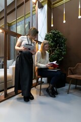 Two women collaborating in a modern office space with creative decor and natural lighting during work hours
