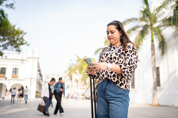 Tourist using smartphone and carrying trolley bag in a colonial city
