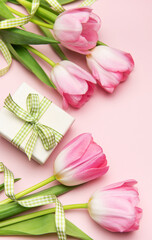 Pink tulips and gift box creating a spring themed flat lay on pink background