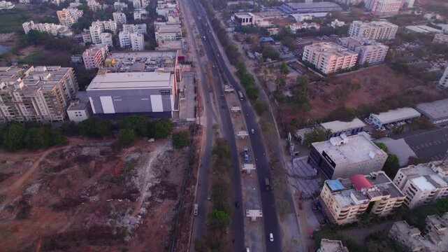 national highway 44 with service road, under Under construction flyover and apartments at suchitra, hyderabad, telangana, india. day time, push in, tilt up, drone shot, 4k.