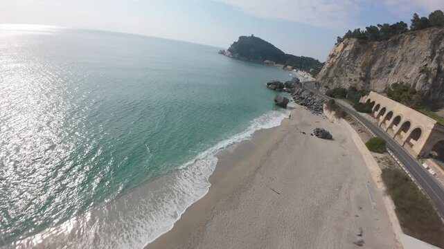 smooth FVP aerial dive toward the beautiful turquoise waters of Spiaggia del Malpasso near the coastal highway